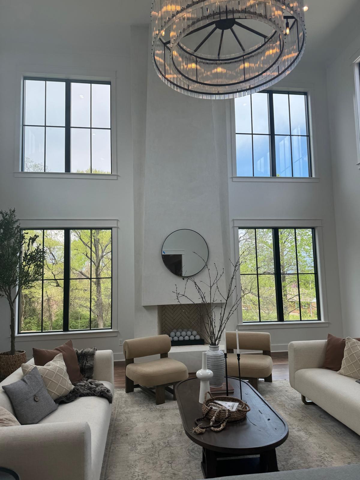 A grand two-story living room with tall windows, freshly painted