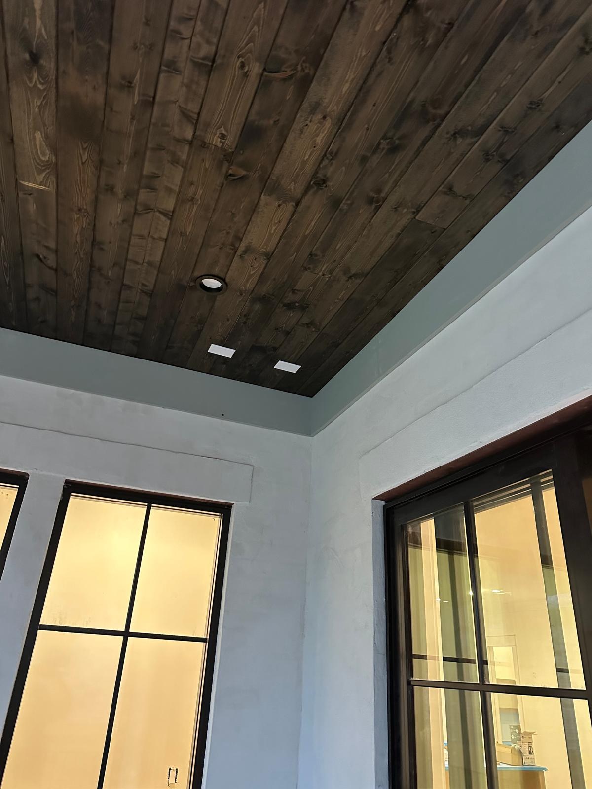 A vaulted wood ceiling and tall windows in a painted home interior