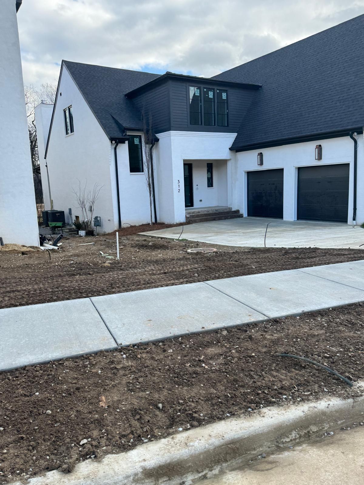 A clean new home exterior with a spotless driveway and walkway