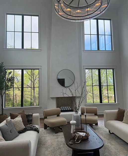 A sunlit living room with large windows and neutral sofas