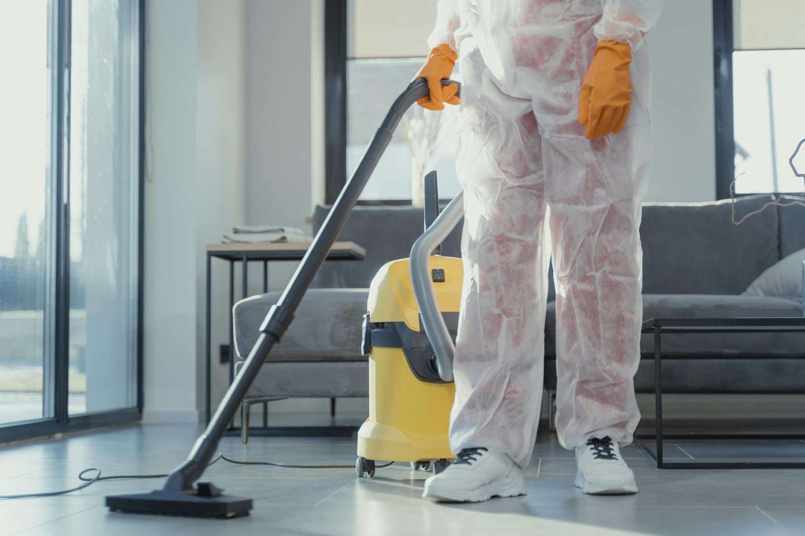 A cleaner vacuuming a bright living room during a deep clean